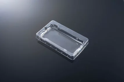 Clear rectangular plastic blister pack tray on a dark reflective surface.