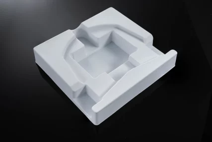 White thermoformed plastic mold tray with custom compartments on a black background.